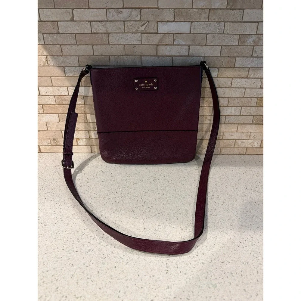 Kate Spade New York pebbled leather crossbody bag in a deep burgundy/wine color.